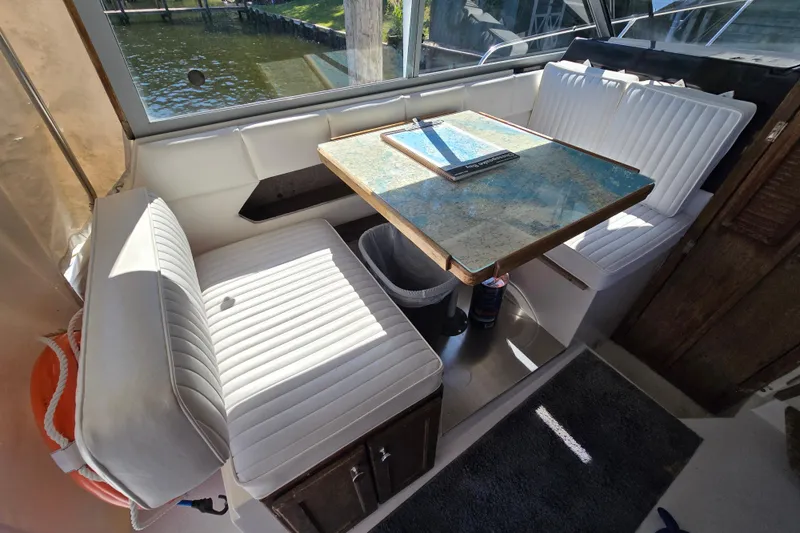 Slide: The Image of Interior of 1984 Bayliner 2802 Trophy boat with white seating and a map-covered table. - 34