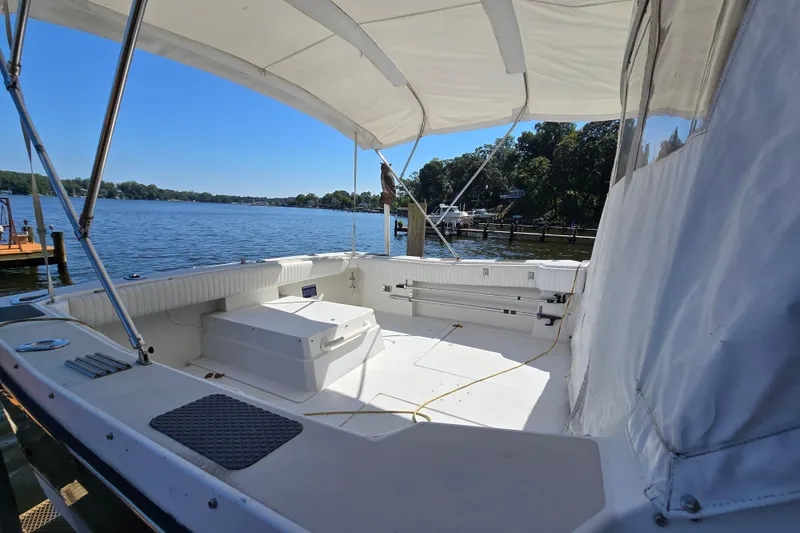 Slide: The Image of 1984 Bayliner 2802 Trophy boat interior with canopy, docked by a scenic lake. - 7