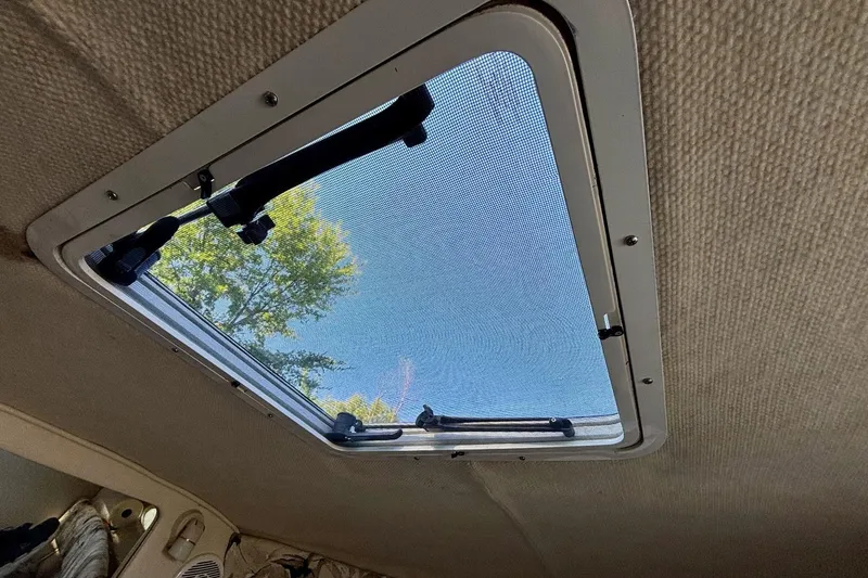Slide: The Image of 1999 Sea Ray 260 Overnighter cabin skylight with mesh screen, view of blue sky and trees. - 14