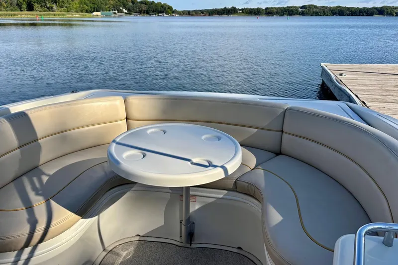 Slide: The Image of 1999 Sea Ray 260 Overnighter boat interior with round table and cushioned seating by the lake. - 18