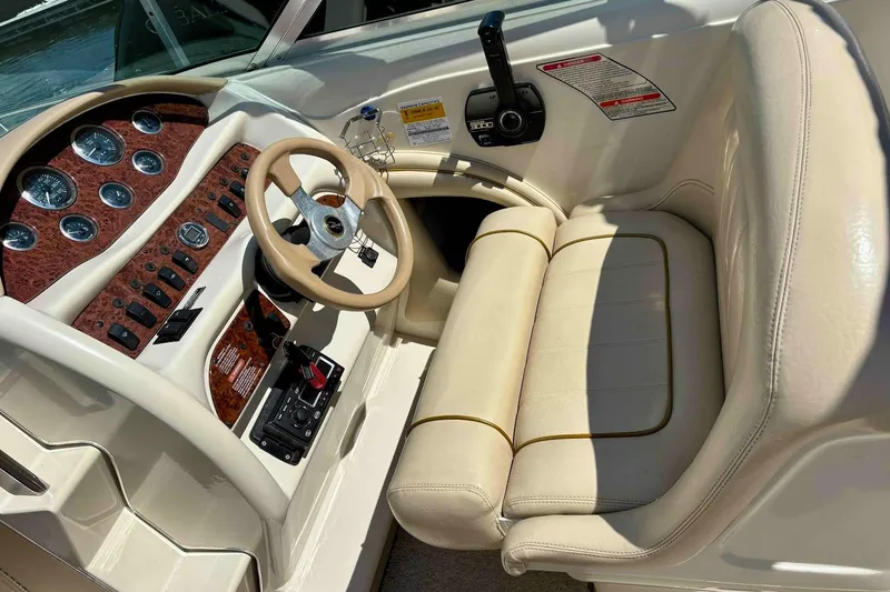 Slide: The Image of 1999 Sea Ray 260 Overnighter boat interior with beige seating and wood-accented dashboard. - 9