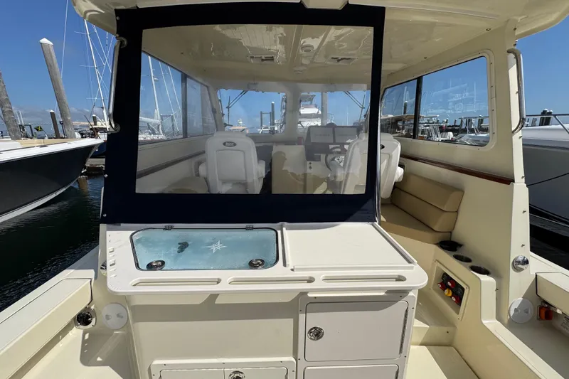 Slide: The Image of 2026 NorthCoast 285 HT boat interior with seating and control panel at marina. - 2