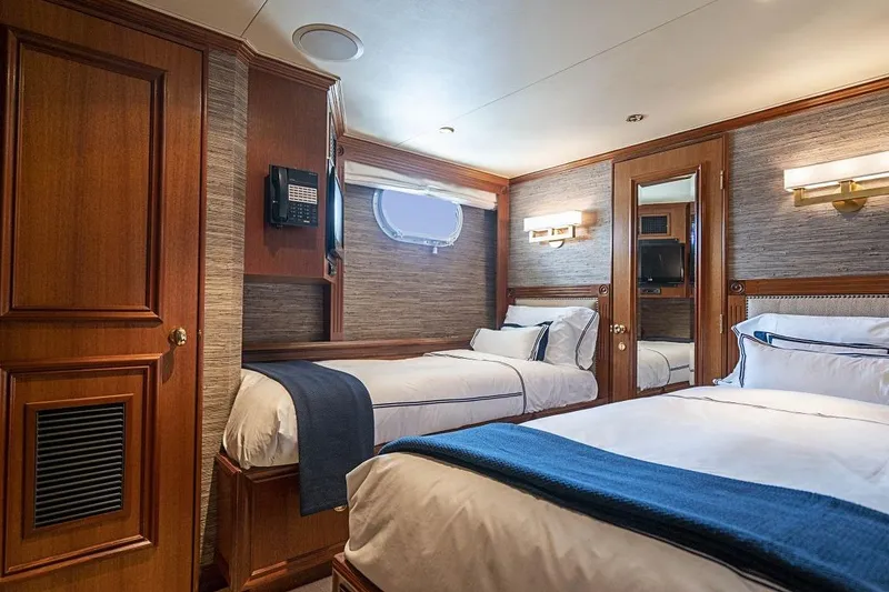 Slide: The Image of Luxurious 2000 Broward Raised Pilothouse yacht bedroom with elegant wood paneling and twin beds. - 19