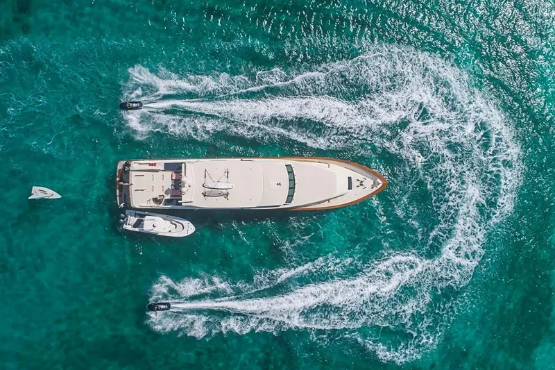 Slide: The Image of Aerial view of 2000 Broward Raised Pilothouse yacht on turquoise water with jet skis. - 29