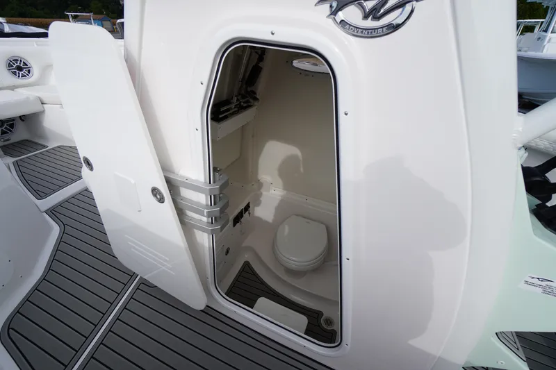 Slide: The Image of 2026 Tidewater 282 CC Adventure boat interior with open door revealing compact marine toilet. - 25