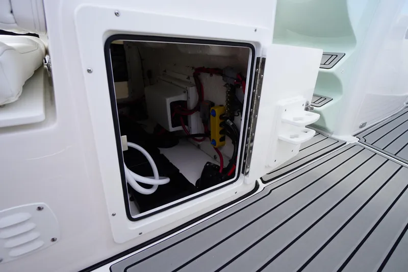 Slide: The Image of Open storage compartment on 2026 Tidewater 282 CC Adventure boat, showing interior wiring and components. - 48