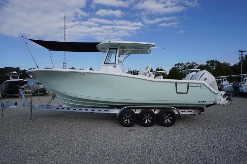Slide: The Image of 2026 Tidewater 282 CC Adventure boat on a trailer, under a clear blue sky. - 98