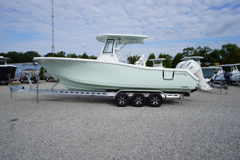 Slide: The Image of 2026 Tidewater 282 CC Adventure boat on trailer, parked on gravel lot. - 99