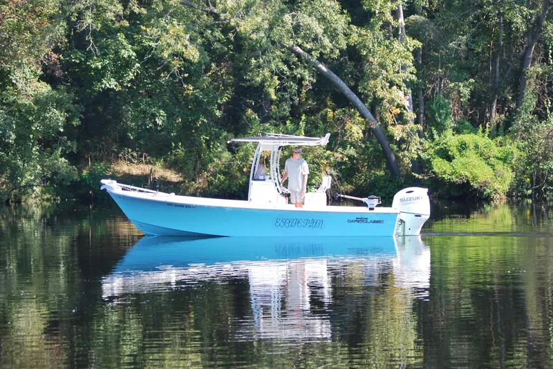 Slide: The Image of 2021 May-Craft 23 Cape Classic boat on calm water, surrounded by lush greenery. - 2