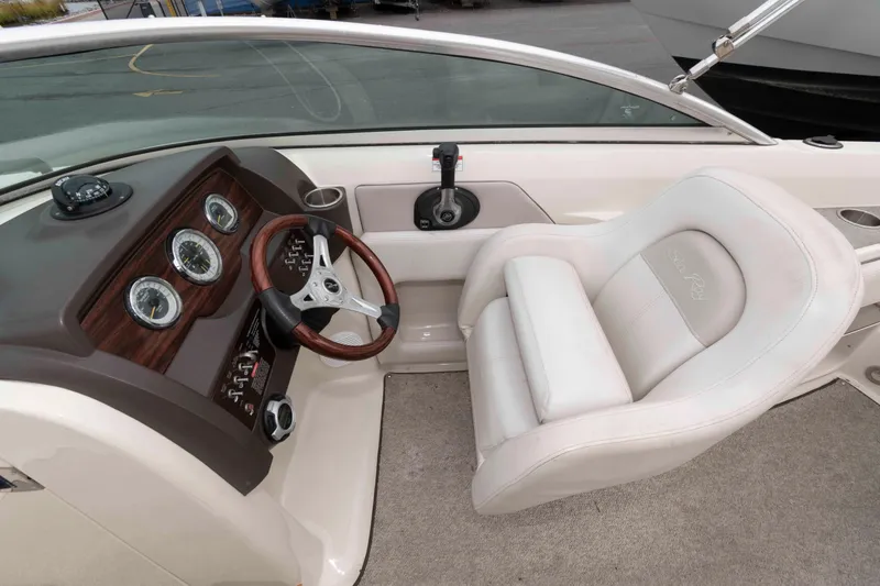 Slide: The Image of 2010 Sea Ray 240 Sundeck helm with wood-accented dashboard and plush captain's chair. - 5