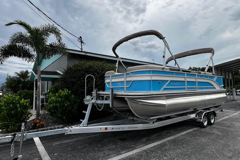 The Image of 2026 Bennington S22 pontoon boat on trailer, parked near tropical plants. - 1
