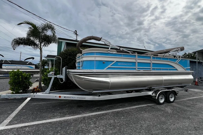 Slide: The Image of 2026 Bennington S22 pontoon boat on trailer, parked outdoors under cloudy sky. - 9