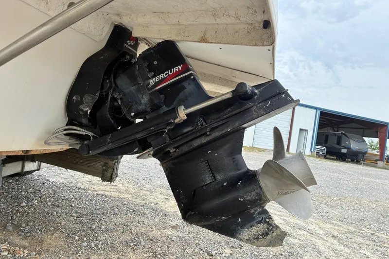 Slide: The Image of 2003 Hurricane 234 SD boat with Mercury outboard motor, parked on gravel. - 11