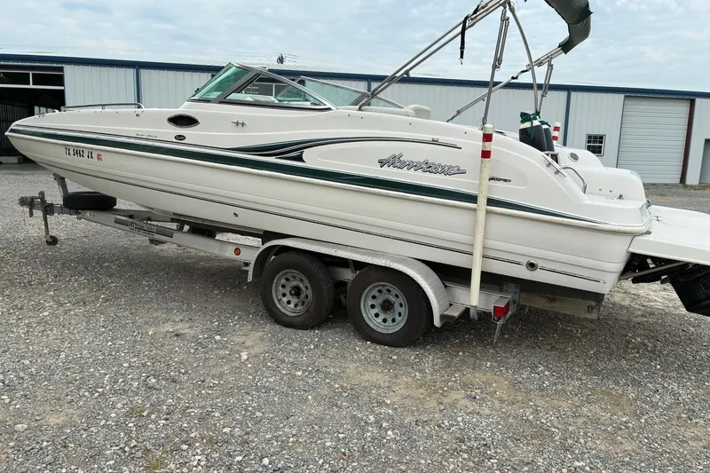 Slide: The Image of 2003 Hurricane 234 SD boat on trailer, parked outdoors near a warehouse. - 2