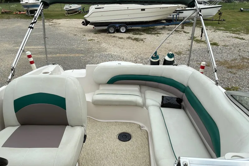 Slide: The Image of 2003 Hurricane 234 SD boat interior with white and green seating, parked on gravel. - 7
