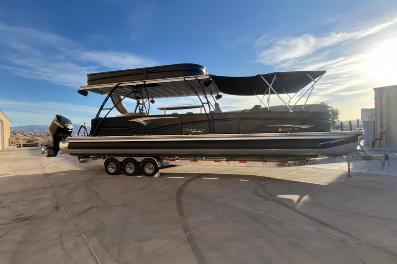 Slide: The Image of 2023 Premier 310 Boundary Waters Revolution Top Deck pontoon boat on trailer, sunny day. - 3