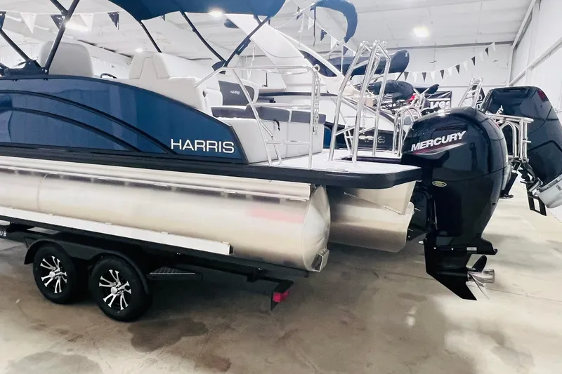 Slide: The Image of 2025 Harris Cruiser 230 Heritage Edition pontoon boat with Mercury outboard motor in showroom. - 17