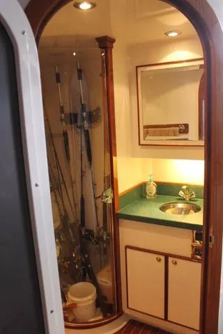 Slide: The Image of 2005 Custom DeSanti Carolina Express boat interior with fishing rods and compact sink area. - 13