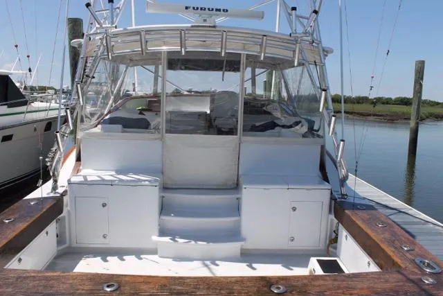 Slide: The Image of Custom 2005 DeSanti Carolina Express boat docked, featuring spacious deck and seating area. - 27