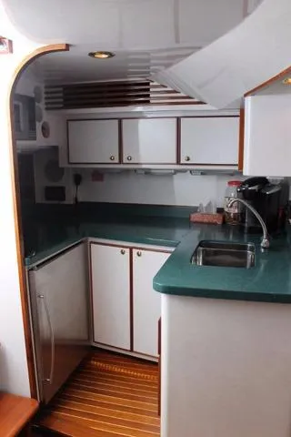 Slide: The Image of Compact kitchen in 2005 Custom DeSanti Carolina Express boat with green countertops and white cabinets. - 8