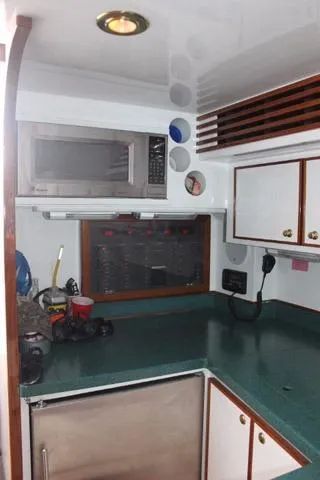 Slide: The Image of 2005 Custom DeSanti Carolina Express boat kitchen with green countertops and white cabinets. - 9