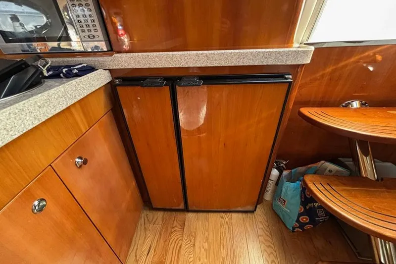 Slide: The Image of 2005 Regal Commodore 4260 yacht interior with wooden cabinetry and compact kitchen appliances. - 22