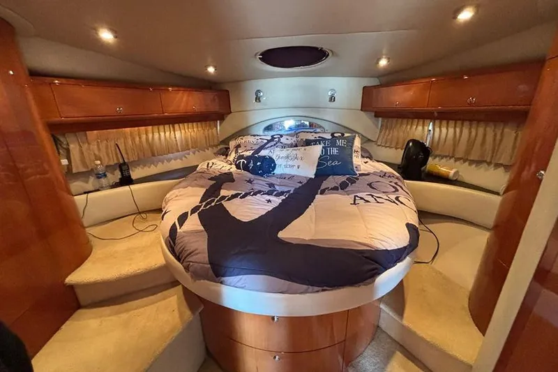 Slide: The Image of Luxurious 2005 Regal Commodore 4260 yacht bedroom with cozy bedding and elegant wood cabinetry. - 24