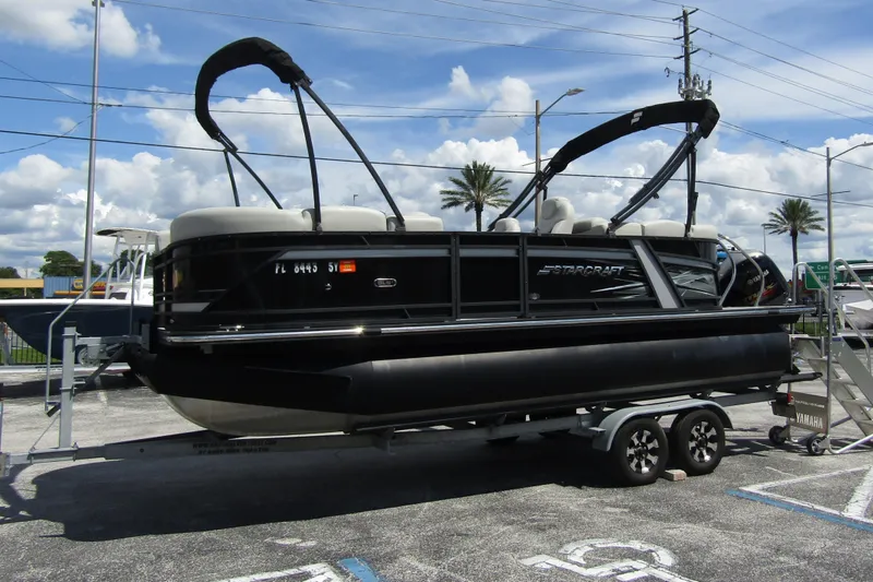 Slide: The Image of 2021 Starcraft SLS 1 pontoon boat on trailer, parked outdoors under a clear sky. - 1