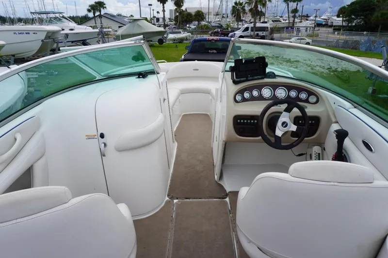 Slide: The Image of 2003 Chaparral 230 SSi boat interior with steering wheel and dashboard, docked near other boats. - 11