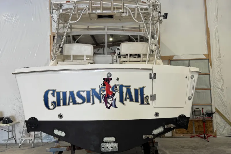 Slide: The Image of 2011 Luhrs 30 Open boat in storage, featuring "Chasin Tail" graphic on the stern. - 5