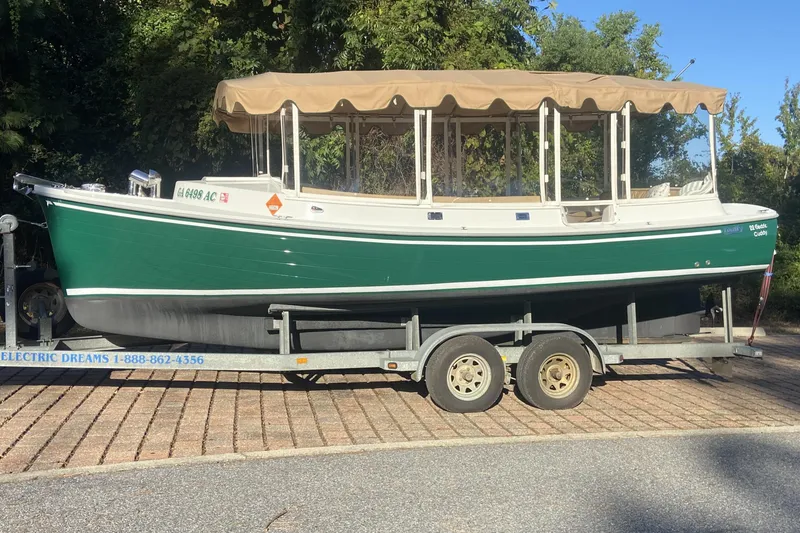The Image of 2007 Duffy 22' Cuddy Cabin boat on trailer, green hull, tan canopy, parked outdoors. - 0