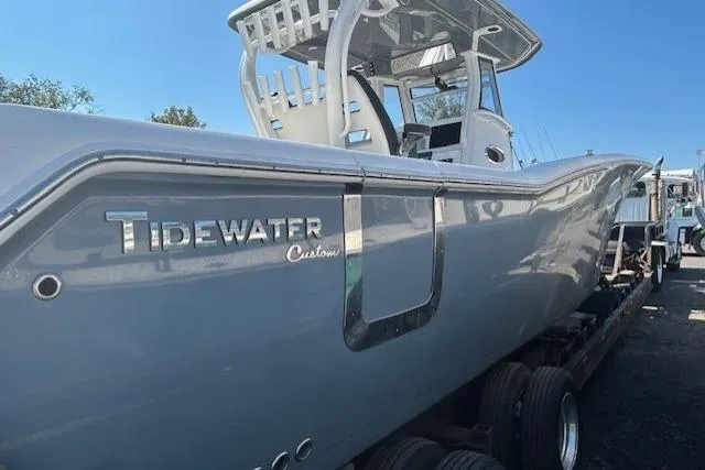 Slide: The Image of 2021 Tidewater 320 CC Adventure boat docked at a marina under a clear blue sky. - 2