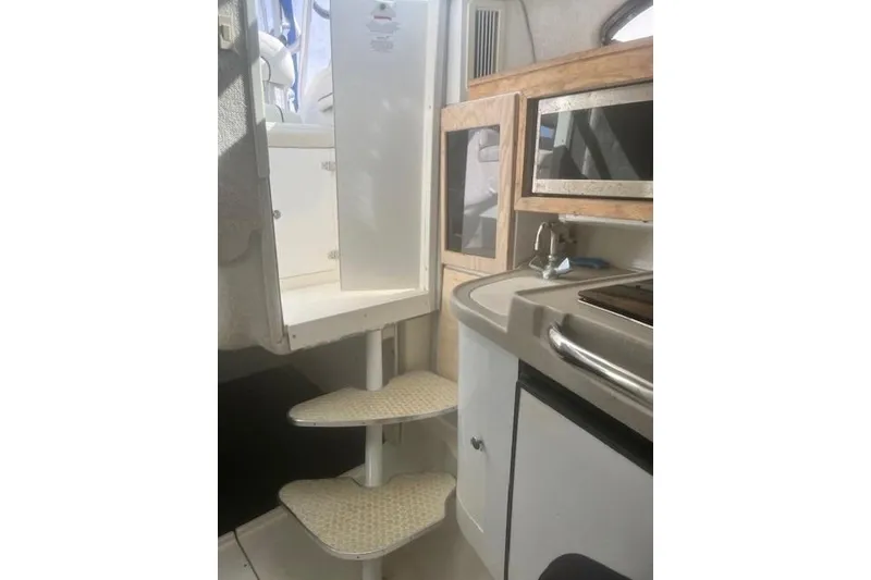 Slide: The Image of Interior of 2000 Wellcraft 2900 Coastal WA boat, featuring compact kitchen and spiral stairs. - 10