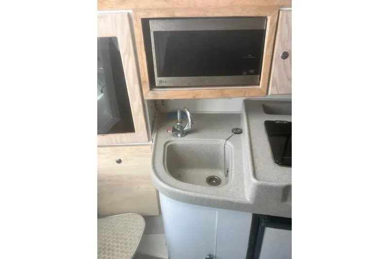 Slide: The Image of Compact kitchen area in a 2000 Wellcraft 2900 Coastal WA boat, featuring a sink and microwave. - 13