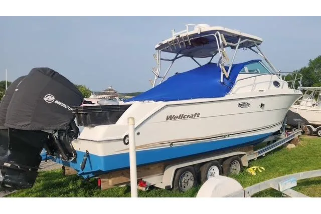 Slide: The Image of 2001 Wellcraft 2900 Coastal WA boat on trailer with blue cover and Mercury outboard. - 22