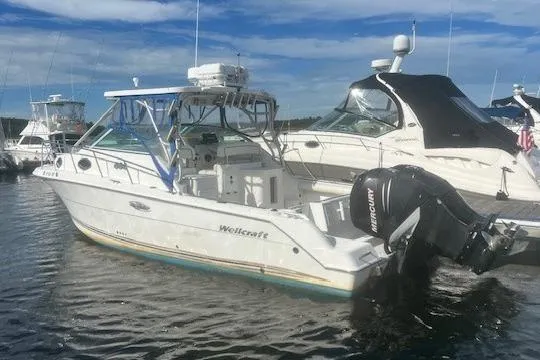 Slide: The Image of 2000 Wellcraft 2900 Coastal WA boat docked with outboard motors, under clear sky. - 3
