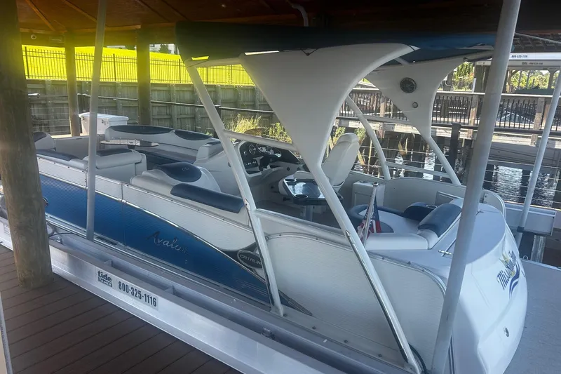 The Image of 2020 Avalon Catalina 2585 pontoon boat docked under a wooden canopy. - 0