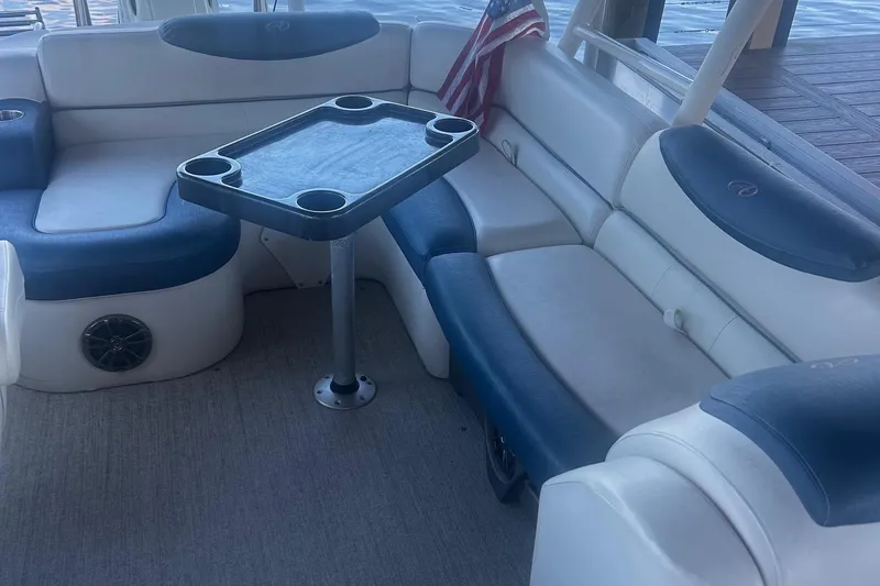 Slide: The Image of 2020 Avalon Catalina 2585 boat interior with seating and table, featuring cup holders and American flag. - 14