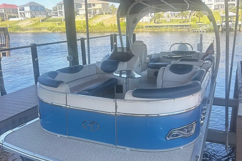 Slide: The Image of 2020 Avalon Catalina 2585 pontoon boat with blue and white seating under a wooden dock. - 2