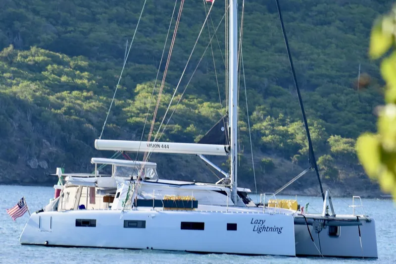 Slide: The Image of Sailing catamaran Vision 444, 2021 model, anchored in scenic bay with lush green hills. - 2