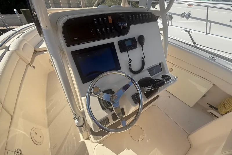 Slide: The Image of 2017 Grady-White Canyon 271 FS boat helm with steering wheel and navigation controls. - 1