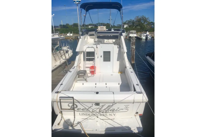 Slide: The Image of 2000 Phoenix 29 SFX boat docked at marina, featuring spacious deck and blue canopy. - 2