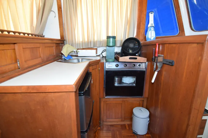 Slide: The Image of 1972 CHB 34 boat kitchen with wooden cabinetry, oven, sink, and fan. - 13