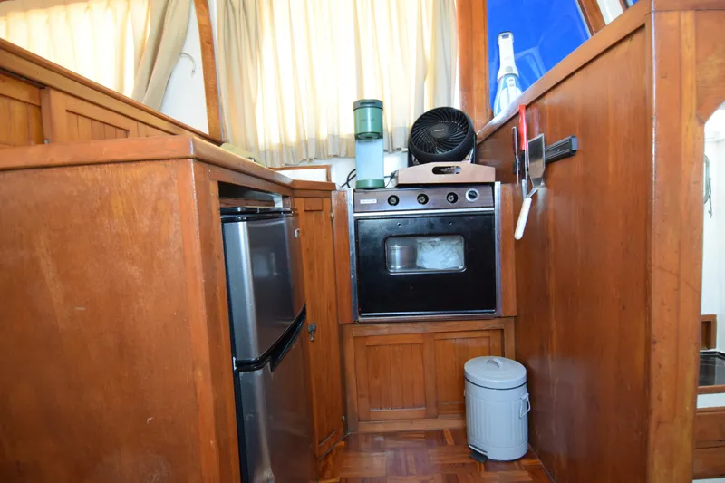 Slide: The Image of Wooden interior of a 1972 CHB 34 boat galley with oven, fridge, and fan. - 17
