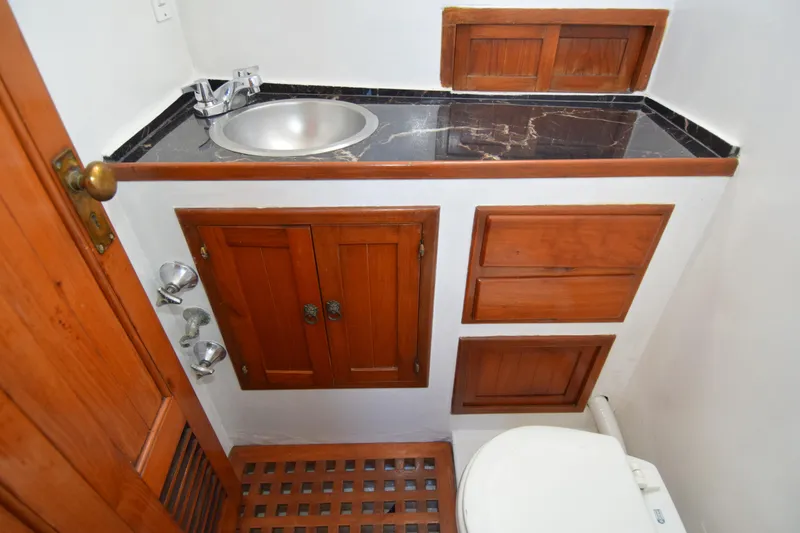 Slide: The Image of 1972 CHB 34 boat bathroom with wooden cabinets, sink, and toilet. - 19