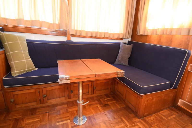 Slide: The Image of Cozy 1972 CHB 34 boat interior with blue cushioned seating and wooden table. - 25