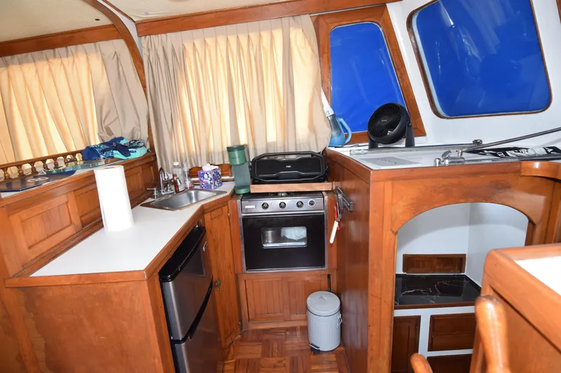 Slide: The Image of 1972 CHB 34 boat interior kitchen with wooden cabinetry, stove, and sink. - 6