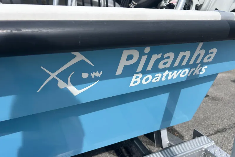 Slide: The Image of Piranha Boatworks logo on a 2025 Piranha Magro P180 boat, blue hull detail. - 13