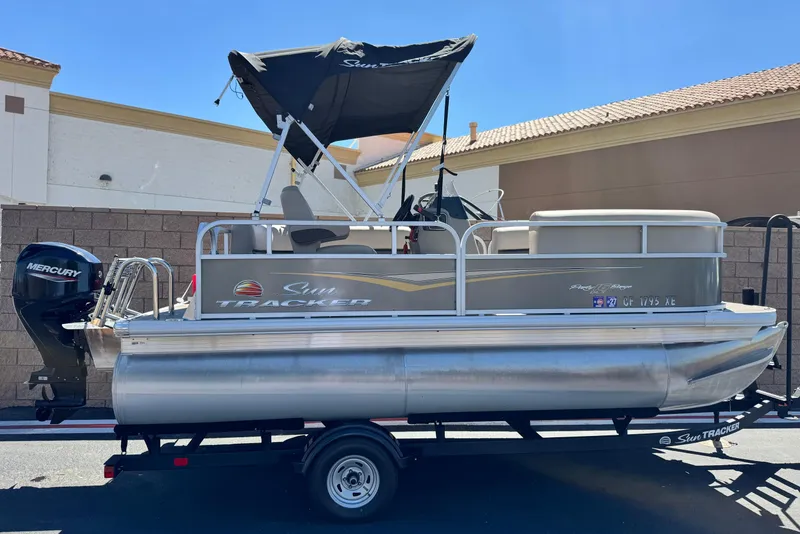 The Image of 2025 Sun Tracker Party Barge 16 DLX pontoon boat with Mercury outboard motor on trailer. - 0