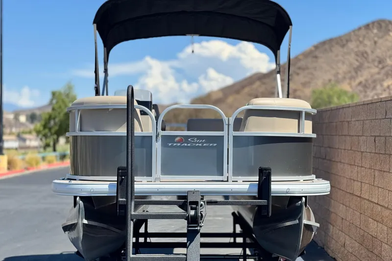 Slide: The Image of 2025 Sun Tracker Party Barge 16 DLX pontoon boat on trailer, scenic mountain backdrop. - 2